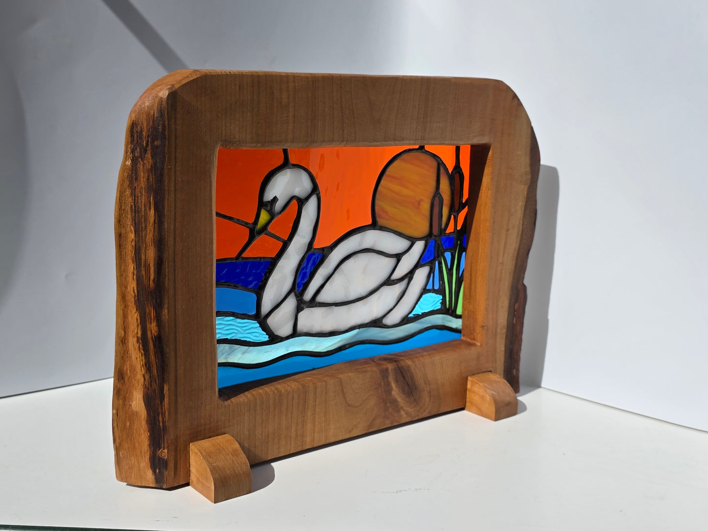 Stained glass 'Swan at Sunset' frames in a solid wood frame.