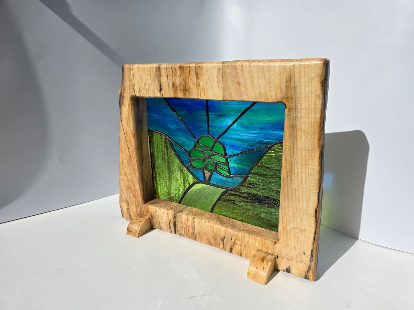 Stained glass 'Aurora at the Sycamore Gap' framed in solid sycamore wood.