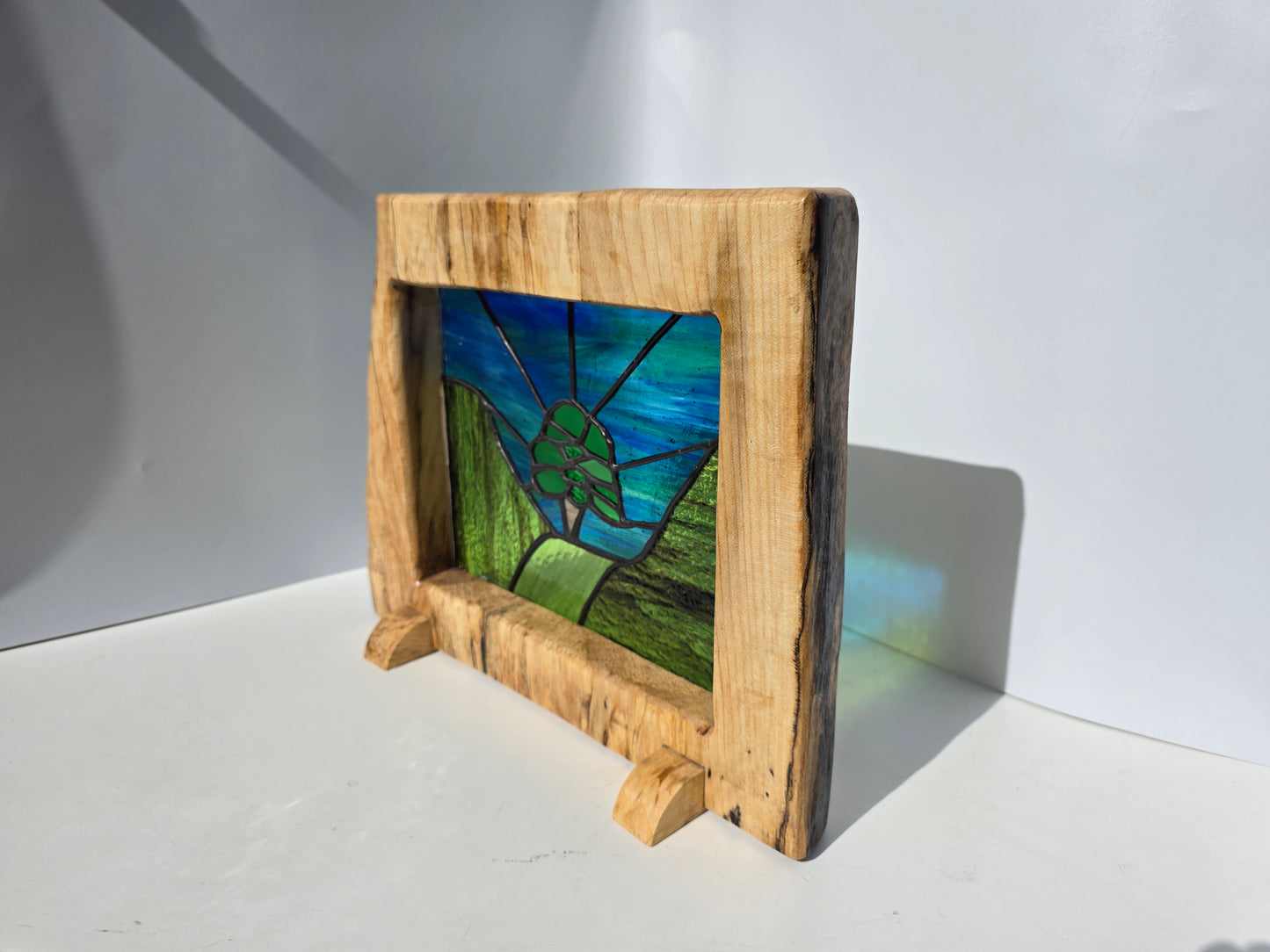 Stained glass 'Aurora at the Sycamore Gap' framed in solid sycamore wood.