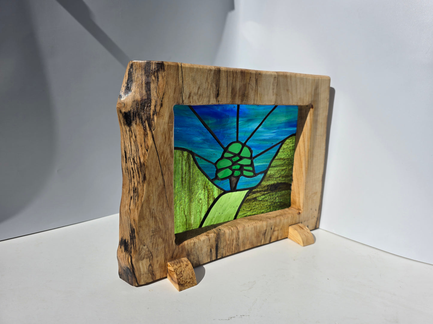 Stained glass 'Aurora at the Sycamore Gap' framed in solid sycamore wood.